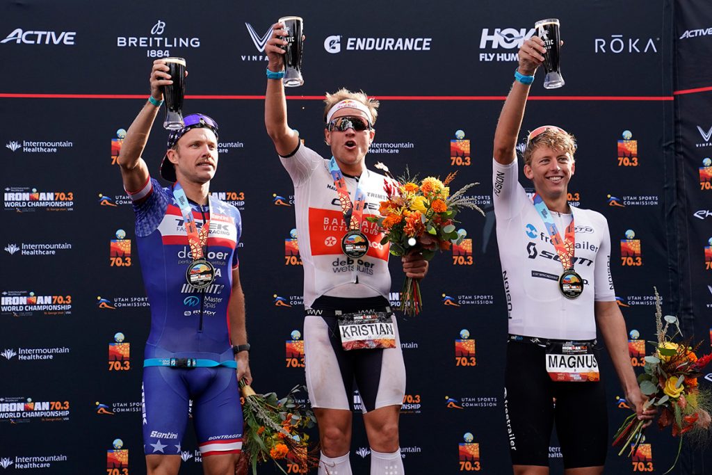 Top three finisher raise glasses of beer on the podium