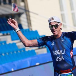 A triathlete finishes while waving a US flag